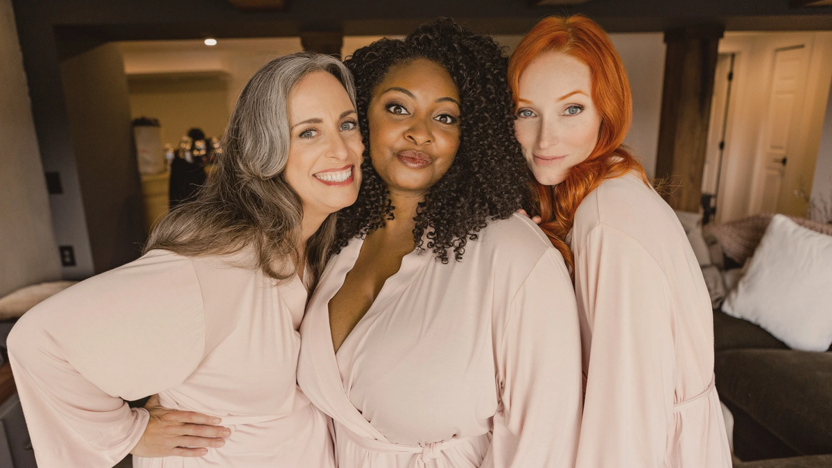 Three smiling women standing together wearing Earthly Threads bamboo pink Everyday Robe